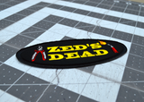 Close up detail of an oval shaped black embroidered patch with the words zed's dead in yellow thread between a pair of pliers and a blowtorch.
