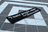 Close up detail of a rectangular black embroidered patch with a quote by Bonecrusher in white thread that says I hate people, man.