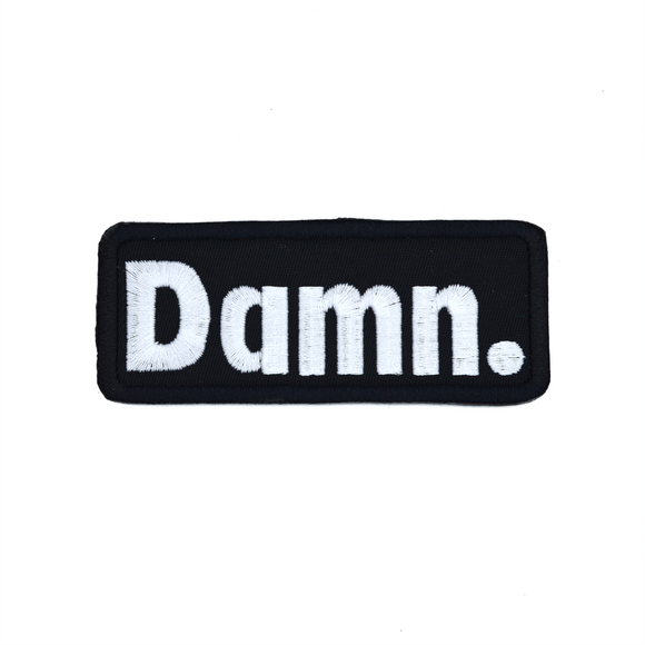 Rectangular black patch with white embroidery spelling the word damn with a period at the end.