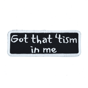 Rectangular black patch with a white border and the words, got that tism in me, embroidered in white thread.