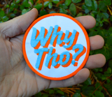 A circular white, blue, and orange embroidered patch with the phrase Why Tho? Shown in the palm of a hand for size reference.