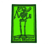 Rectangular lime green and dark green embroidered patch of a smoking skeleton in a medieval woodcut design style with the phrase doeth whatever spelled out in old English lettering.