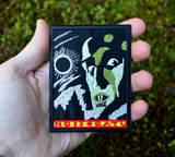 A rectangular embroidered patch of the movie poster for the classic silent horror film Nosferatu. Shown in the palm of a hand for size reference.
