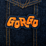 Orange and black embroidered logo patch for the classic Kaiju monster movie Gorgo. Shown on a denim jacket.