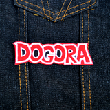 A red, black, and white embroidered logo patch for Dogora, the classic Kaiju monster movie. Shown on a denim jacket.