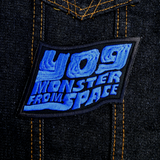 Blue and black embroidered logo patch for the classic kaiju monster movie, Yog, Monster from Space. Shown on a a denim jacket.