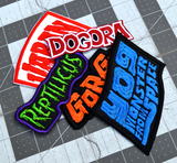 A collection of five obscure kaiju monster movie embroidered logo patches, including Reptilicus, Varan, Dogora, Gorgo, and Yog, the Monster from Space.