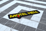 Close up detail of a rectangular black and yellow embroidered logo patch for the classic comedy horror slasher movie Motel Hell.