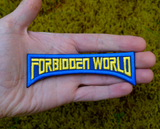 Embroidered logo patch for the classic horror sci-fi movie 'Forbidden World' with blue border and yellow text. Shown in the palm of a hand for size reference.