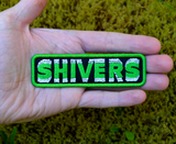 Rectangular green, black, and white, embroidered patch with 'SHIVERS' text on a green border, based on the classic horror sci-fi movie. Shown in the palm of a hand for size reference.