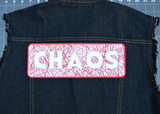 Rectangular embroidered patch with the word chaos cut out of random lines of red thread on white fabric. Shown on the back of a denim vest.