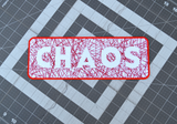 Rectangular embroidered patch with the word chaos cut out of random lines of red thread on white fabric.