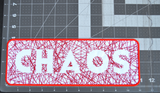Rectangular embroidered patch with the word chaos cut out of random lines of red thread on white fabric. Shown on a measuring table with a length of 11 inches and a height of 4 inches.