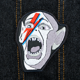 An embroidered patch of the Bat Boy from the classic Weekly World News tabloid with a David Bowie red and blue lightening bolt painted on his face.