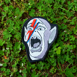 An embroidered patch of the Bat Boy from the classic Weekly World News tabloid with a David Bowie red and blue lightening bolt painted on his face.