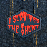 Red on black embroidered patch that says I survived the shunt, in reference to the horror movie, Society.
