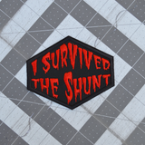 Red on black embroidered patch that says I survived the shunt, in reference to the horror movie, Society.