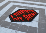 Close up detail of a red on black embroidered patch that says I survived the shunt, in reference to the horror movie, Society.