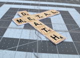 Close up detail of an embroidered patch resembling wooden scrabble tiles spelling the words 'DEATH METAL'.