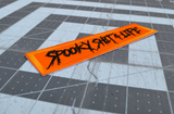 Close up detail of a rectangular orange embroidered patch with the text, spooky shit 4 life, stitched in black thread.