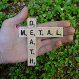 Embroidered patch resembling wooden scrabble tiles spelling the words 'DEATH METAL'. Held in the palm of a hand for size reference.