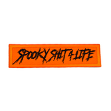 Rectangular orange embroidered patch with the text, spooky shit 4 life, stitched in black thread.