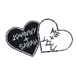 Two heart-shaped embroidered patches with personalized names for couples. One is white stitching on black fabric, one is black stitching on white fabric.