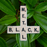 An embroidered patch that says black metal spelled out in Scrabble letters in the shape of an inverted cross.