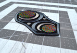 Close up detail of an oblong embroidered patch with abstract geometric arcs and circles in grey, black, and multi-color thread.