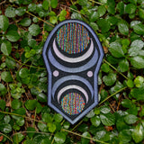An oblong embroidered patch with abstract geometric arcs and circles in grey, black, and multi-color thread.