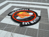Close up detail of a round-shaped embroidered patch with a red circle and slash over a plate of pancakes surrounded by the words, fuck pancakes, eat waffles.