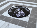 Close up detail of a circular white on black embroidered patch of a raven screaming, I said never-fucking-more!
