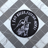 Circular white on black embroidered patch of a raven screaming, I said never-fucking-more!