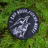 Circular white on black embroidered patch of a raven screaming, I said never-fucking-more!