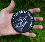 Circular white on black embroidered patch of a raven screaming, I said never-fucking-more! Held in the palm of a hand for size reference.