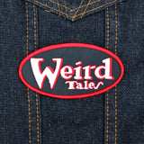 Oval shaped embroidered patch on black fabric, a red border and the logo for the classic strange fiction magazine, Weird Tales stitched in white and red.