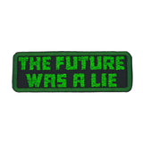 A rectangular embroidered patch on black fabric and a green border, with the words 'the future was a lie' in green block letters.