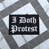 A rectangular black embroidered patch with white Gothic lettering that reads 'I Doth Protest'.