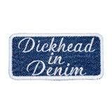 A rectangular embroidered patch on denim fabric with a white border and white lettering that reads, 'Dickhead in denim'.