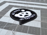 Close up detail of a black embroidered patch in the shape of a chat bubble with an evil-looking version of the reddit logo and the words, 'No Mods, No Masters'.