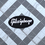 An oval-shaped black embroidered patch with the word 'Gibsiphone' stitched in white, resembling the logo for Gibson and Epiphone guitars.