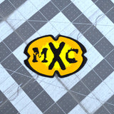 A black and yellow oval-shaped logo patch for the comedy tv show MXC.