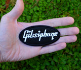 An oval-shaped black embroidered patch with the word 'Gibsiphone' stitched in white, resembling the logo for Gibson and Epiphone guitars. Held in the palm of a hand for size reference.
