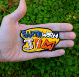An embroidered patch made from the logo of the classic platformer video game Earthworm Jim. Held in the palm of a hand for size reference.
