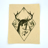 A rectangular off-white fabric patch featuring a dark green graphic print of an antlered figure holding a dagger, surrounded by a diamond border.