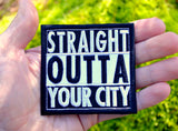 A square shaped white and black embroidered patch in the Straight Outta Compton format that can be customized with personal text. Shown in the palm of a hand for size reference.