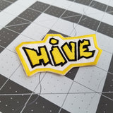 Embroidered logo patch for the abstract boardgame Hive in yellow and black.