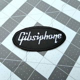 White on black Gibsiphone embroidered patch, a parody mashup of Gibson and Epiphone guitars.
